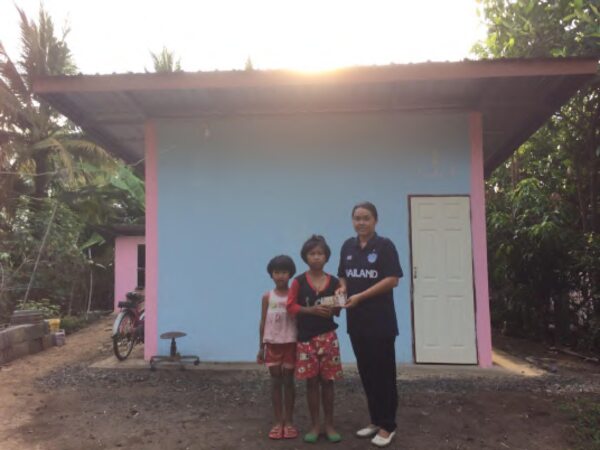 Nong Prae and Nong Noon in front of their new home